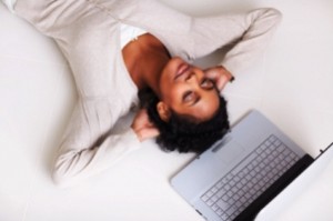 Top view of a relaxed pretty girl lying by laptop on floor